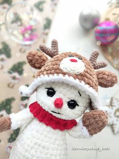 a crocheted snowman with reindeer hat and scarf on it's head