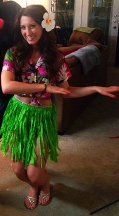 a woman in a green hula skirt standing next to a man wearing a hawaiian shirt