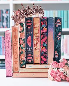 an assortment of books with pink flowers on top