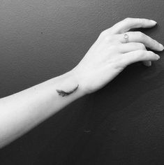 a person's arm with a small bird tattoo on the left side of it