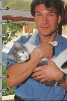 a man holding two cats in his arms