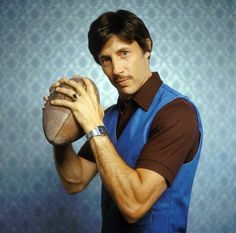 a man holding a football in his right hand and looking at the camera with an intense look on his face