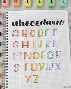 an open notebook with different colored markers and writing on the pages that spell out alphabets