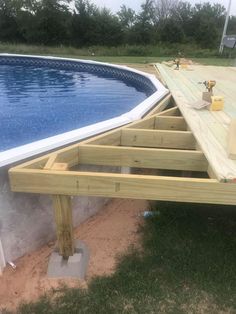 an above ground swimming pool being built on the side of a house with wooden decking