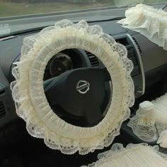 the interior of a car decorated with white lace and ruffles, including a steering wheel cover