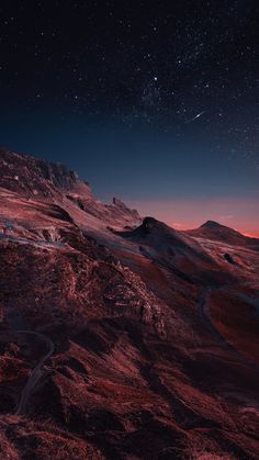 the night sky is lit up by stars above some hills and mountains with snow on them