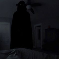 a person in a dark room with a light on and a bat hanging from the ceiling