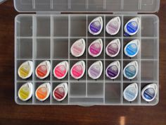 an open plastic container filled with lots of different colored inks on top of a wooden table