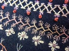 an embroidered piece of cloth with flowers and leaves on it