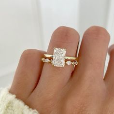 a woman's hand with a diamond ring on top of her finger and an engagement band