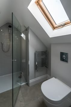 a white toilet sitting under a skylight in a bathroom