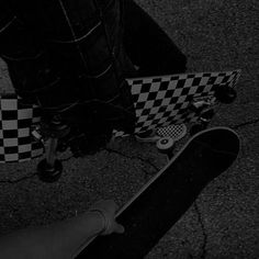 black and white photograph of skateboard on pavement with checkerboard pattern in background