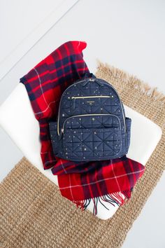 a blue backpack sitting on top of a white plate next to a red and black plaid blanket