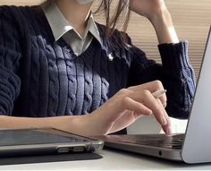 a woman sitting in front of a laptop computer wearing a face mask on her head