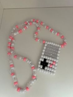 a beaded necklace with a black cross on it and pink beads around the neck