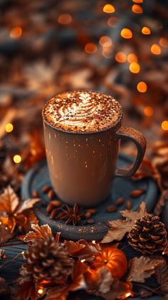 a cup of hot chocolate on top of a blue saucer surrounded by autumn leaves