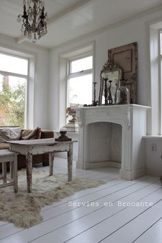 a living room filled with furniture and a fire place in front of two windows on the wall