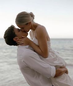 a man and woman kissing on the beach