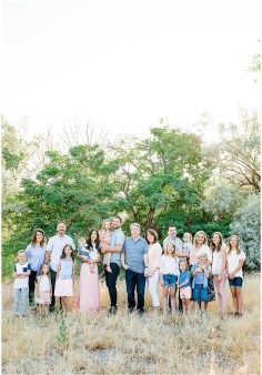 a large group of people are standing in the grass and posing for a family photo