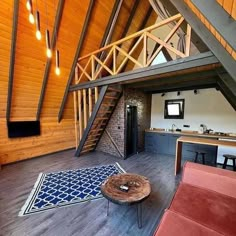 an open loft with wooden walls and stairs leading up to the second floor, along with red couches