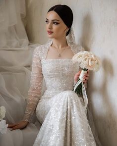 a woman in a white dress holding a bouquet of flowers and wearing a tiara