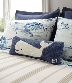 a bed with blue and white pillows on top of it next to a window sill