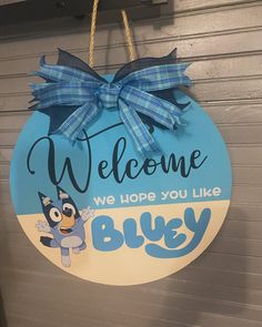 a welcome sign hanging from the side of a building with a blue ribbon on it