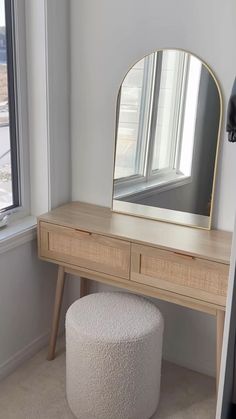 a white stool sitting next to a wooden table with a mirror on top of it