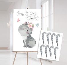 an easel with two greeting cards on it next to the easel is a drawing of a cat