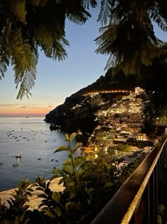 the ocean is lit up at night with boats in the water and trees around it