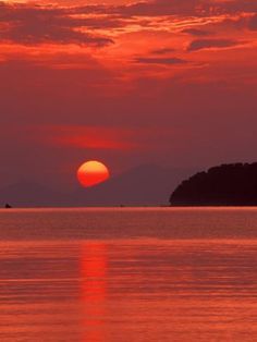 the sun is setting over an island in the ocean