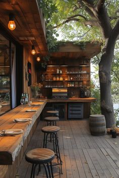 an outdoor bar with wooden tables and stools next to a tree on the deck