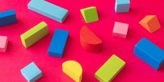 colorful wooden blocks and shapes on a pink background