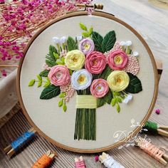 a close up of a embroidery on a table with flowers and crochet needles