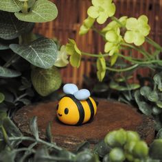 a yellow and black bee figurine sitting on top of a piece of wood