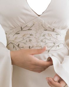 a woman in a white dress holding onto her jacket