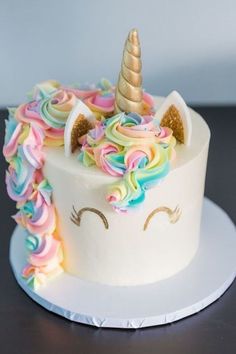 there is a white cake with rainbow icing and a unicorn horn on top