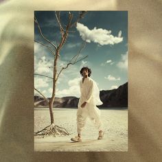 a man standing next to a tree in the desert