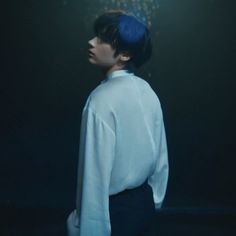 a man with blue hair standing in the dark