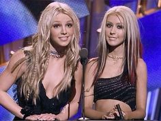 two beautiful young women standing next to each other in front of a microphone on stage