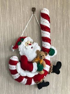 a santa clause hanging on the wall with two stuffed animals in it's arms