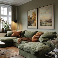 a living room with green couches and paintings on the wall above them, along with a coffee table