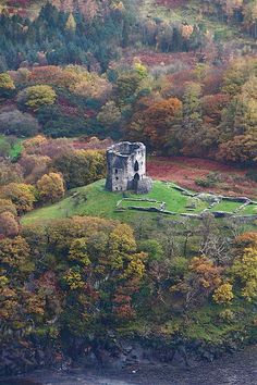 an aerial view of a castle surrounded by trees in the fall season, with autumn foliage surrounding it