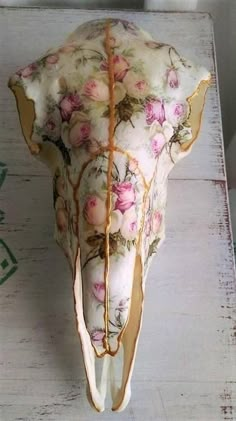 an elephant's head with flowers on it is sitting on a white wooden table