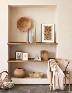 a shelf with vases, baskets and pictures on it next to a wicker basket