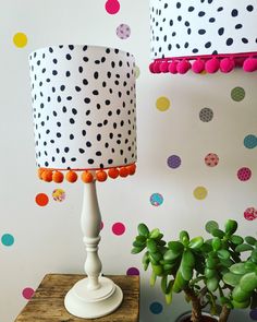 two polka dot lamps on a table next to a potted plant and wallpaper