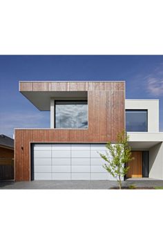 a modern house with wood siding and white garage doors