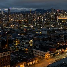 an aerial view of a city at night with the lights on and buildings lit up