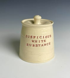 a ceramic jar with the words suspicious white substance on it's lid and red lettering