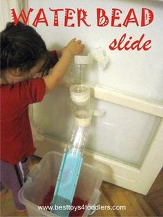 a young child is playing with water beads on the side of a refrigerator freezer